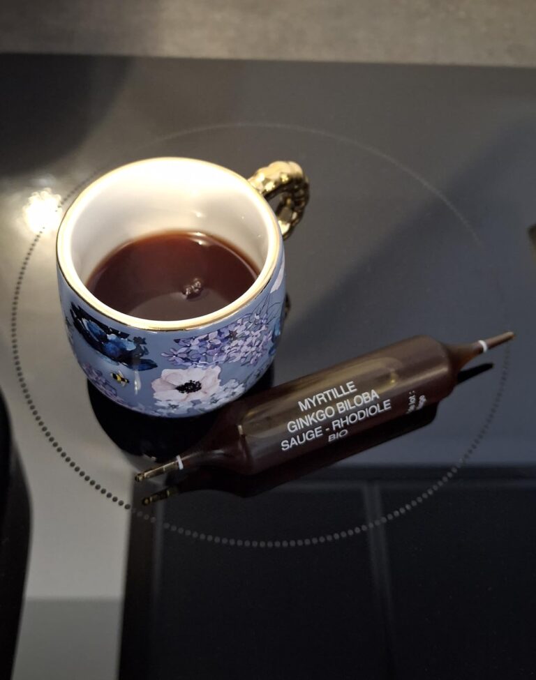 Une ampoule de complément alimentaire et une tasse de boisson, sur une plaque de cuisson.