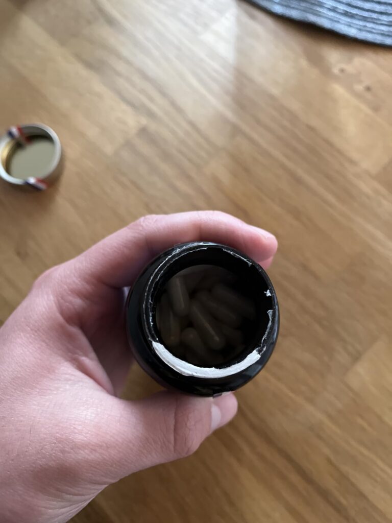 Une main tenant un flacon ouvert, montrant les capsules à l'intérieur.