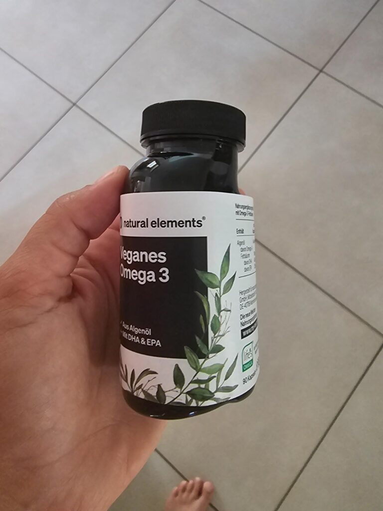 Une main tient le flacon de compléments alimentaires Omega 3, montrant l'étiquette principale.