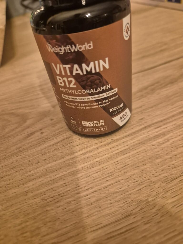 Bouteille de vitamine B12 WeightWorld posée sur une table en bois clair. Angle différent de l'image 1.
