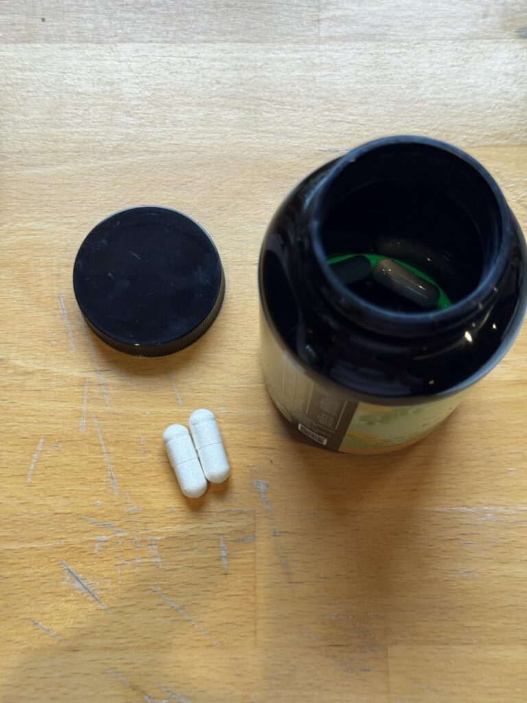 Vue de dessus d'une bouteille de pilules ouverte, avec deux pilules blanches à côté