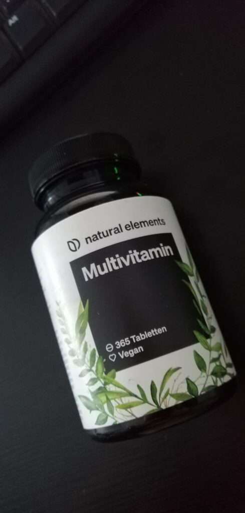 Le flacon de multivitamines posé sur une surface sombre, montrant le même flacon que le visuel précédent.