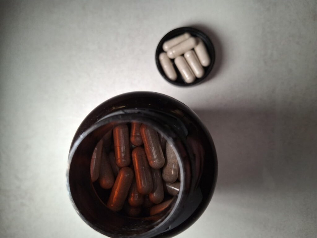 Vue du dessus de la bouteille ouverte, montrant les gélules à l'intérieur et quelques gélules dans le bouchon.