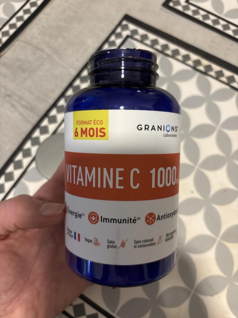 Bouteille de vitamine C tenue dans la main, montrant l'étiquette et le format.