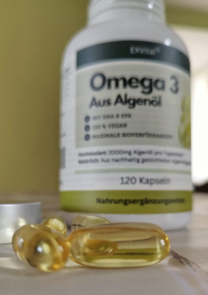Vue en plongée des gélules et du flacon d'Omega 3. Les gélules sont au premier plan, devant le flacon flou.