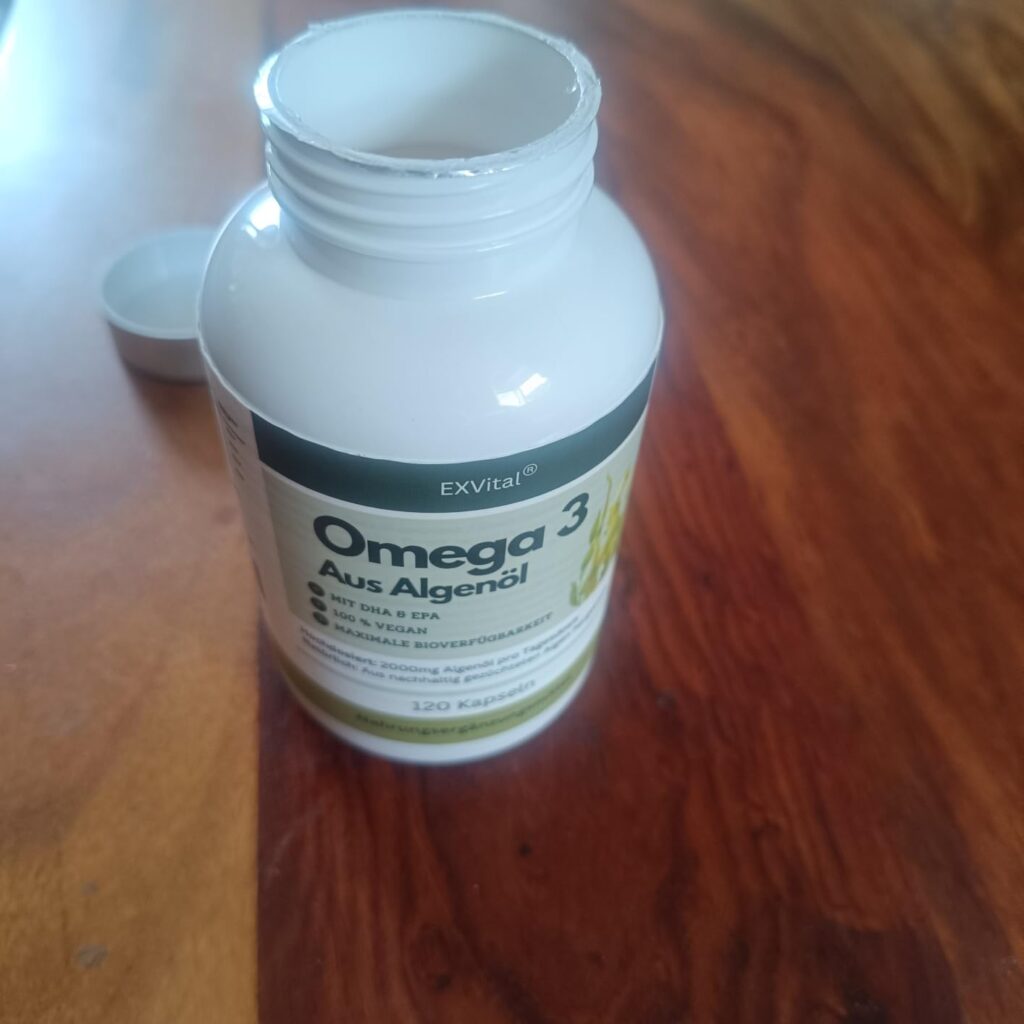 Le flacon d'Omega 3 vide, posé sur une table en bois.