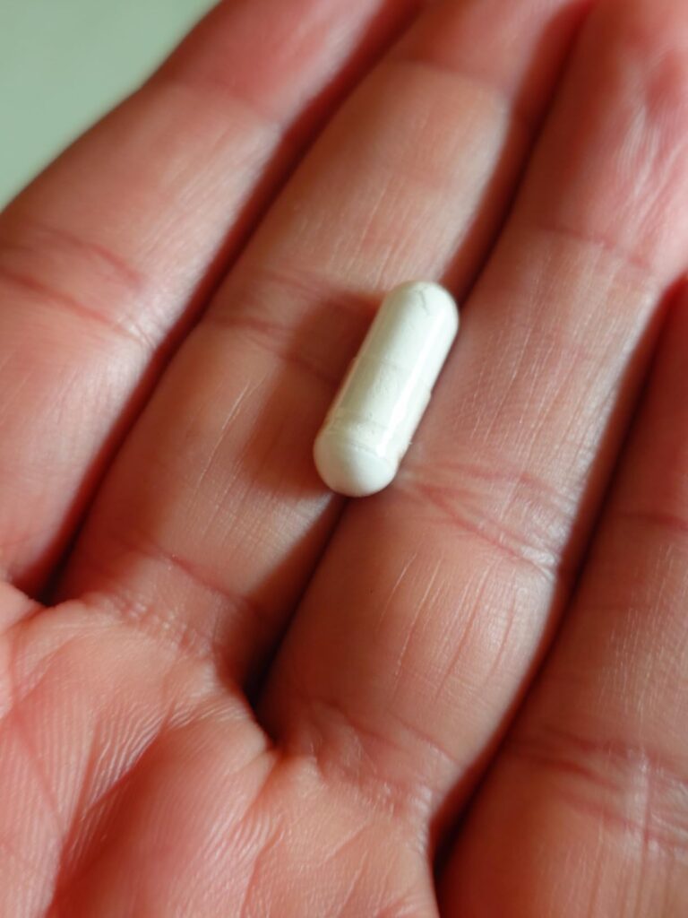 Une capsule de zinc bisglycinat tenue dans la paume de la main.