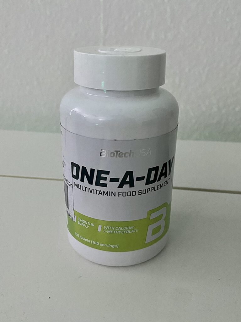 Bouteille de compléments alimentaires 'One-A-Day' de BioTechUSA, posée sur une surface.