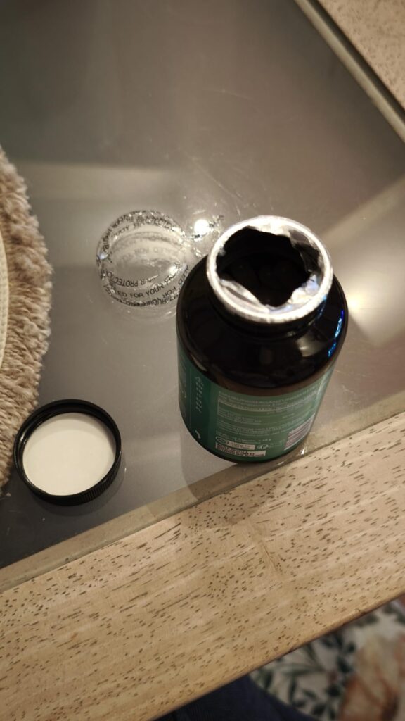 Bouteille de compléments alimentaires ouverte, vue du dessus.