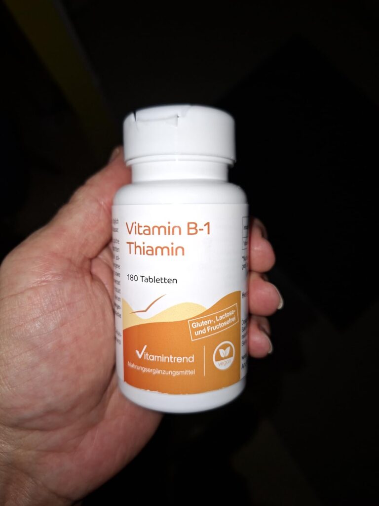 Une main tenant la bouteille de vitamines B1.
