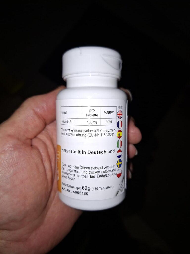 Une main tenant la bouteille de vitamines B1, montrant le dos de la bouteille.