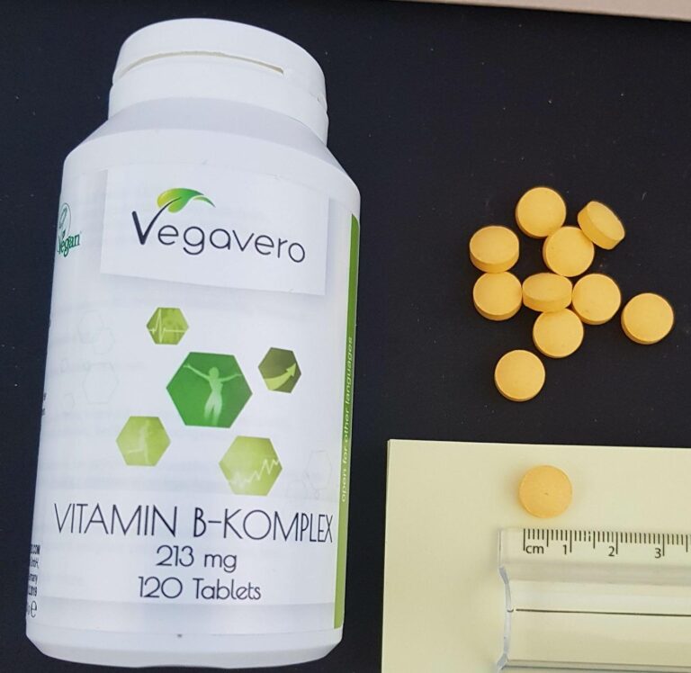 Vue du flacon et de quelques comprimés de vitamine B-Komplex, dont un est à côté d'une règle pour donner une idée de la taill...