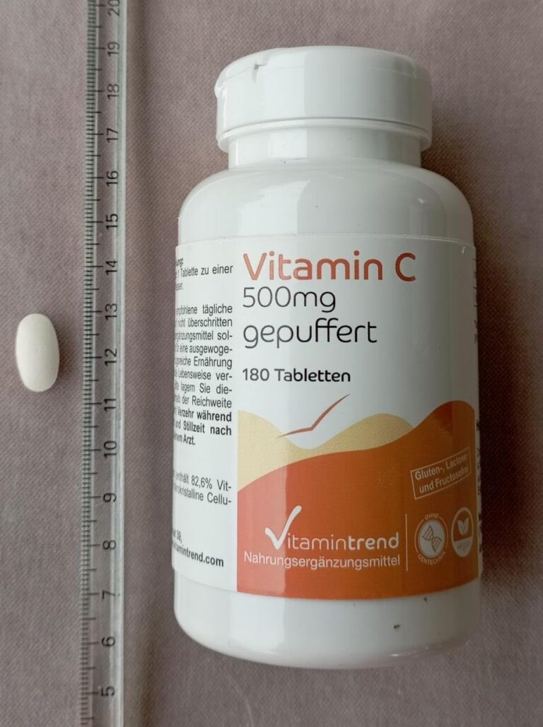 Flacon de vitamine C et un comprimé posé à côté d'une règle graduée.