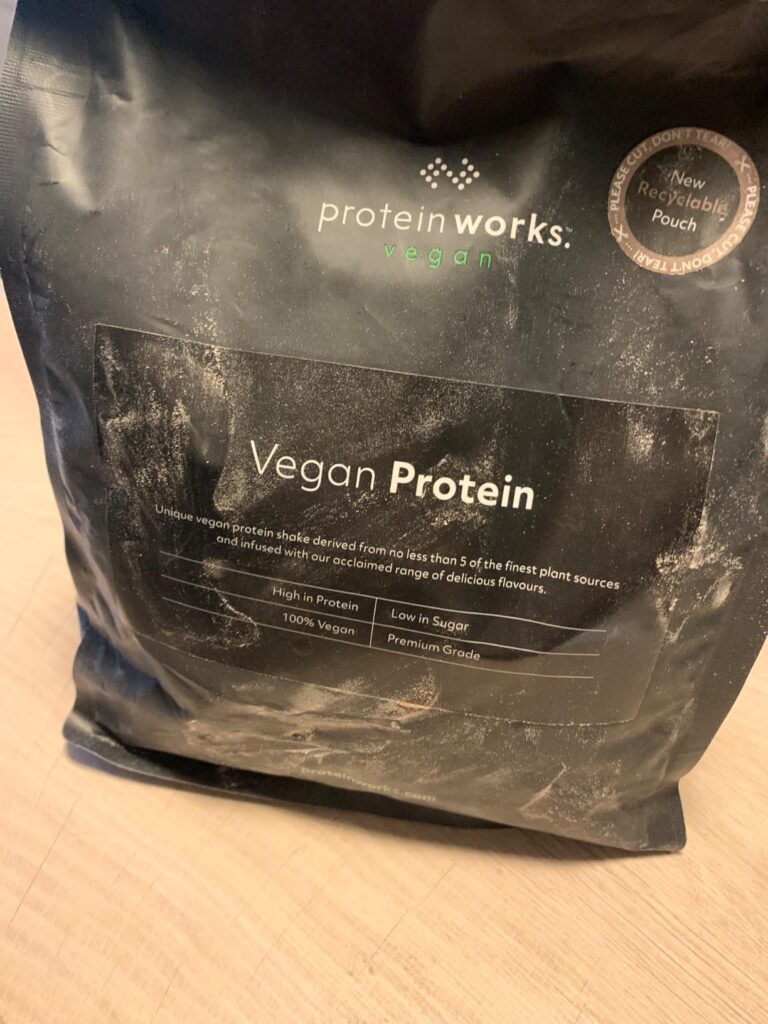 Vue d'ensemble du sachet de Vegan Protein 360 de The Protein Works, posé sur un support clair, l'emballage est sale, on peut...