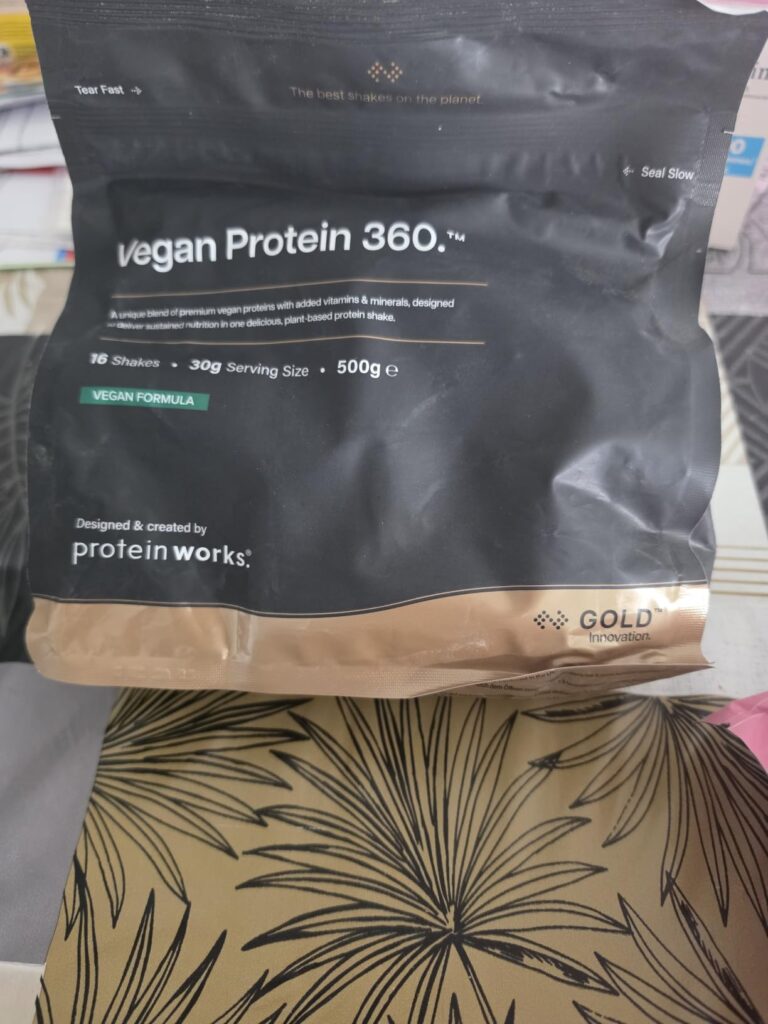 Vue d'ensemble du sachet de Vegan Protein 360 de The Protein Works, posé sur un support clair, l'emballage est sale, une part...