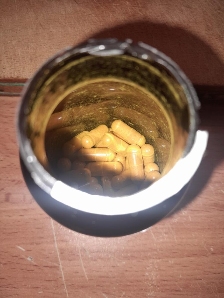 Vue du dessus d'un pot de compléments alimentaires, montrant les capsules à l'intérieur.