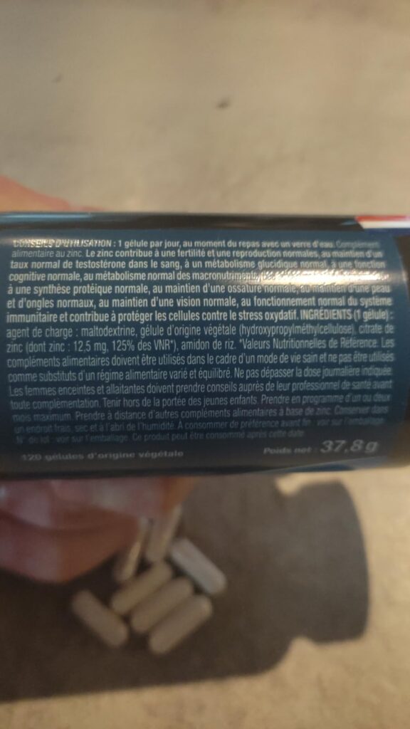 Gros plan sur l'étiquette du flacon de complément alimentaire, qui présente la liste des ingrédients et les informations nutr...
