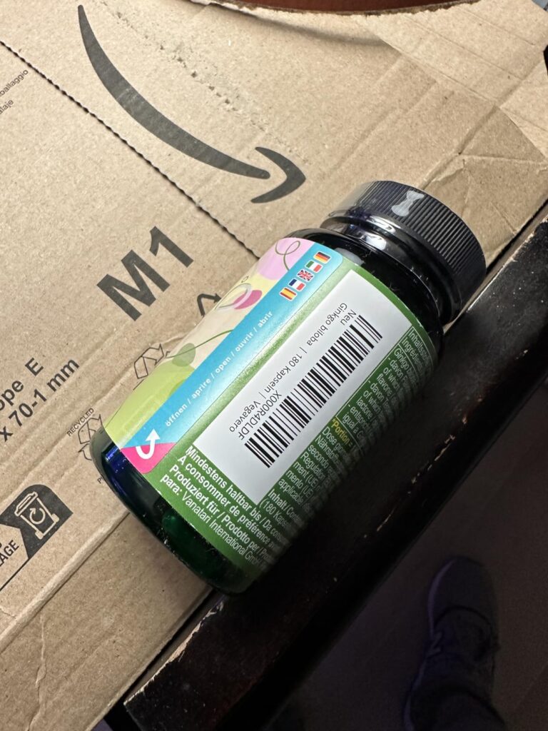 La bouteille de compléments alimentaires posée sur un carton Amazon. On y voit le code barre et une partie de l'étiquette.