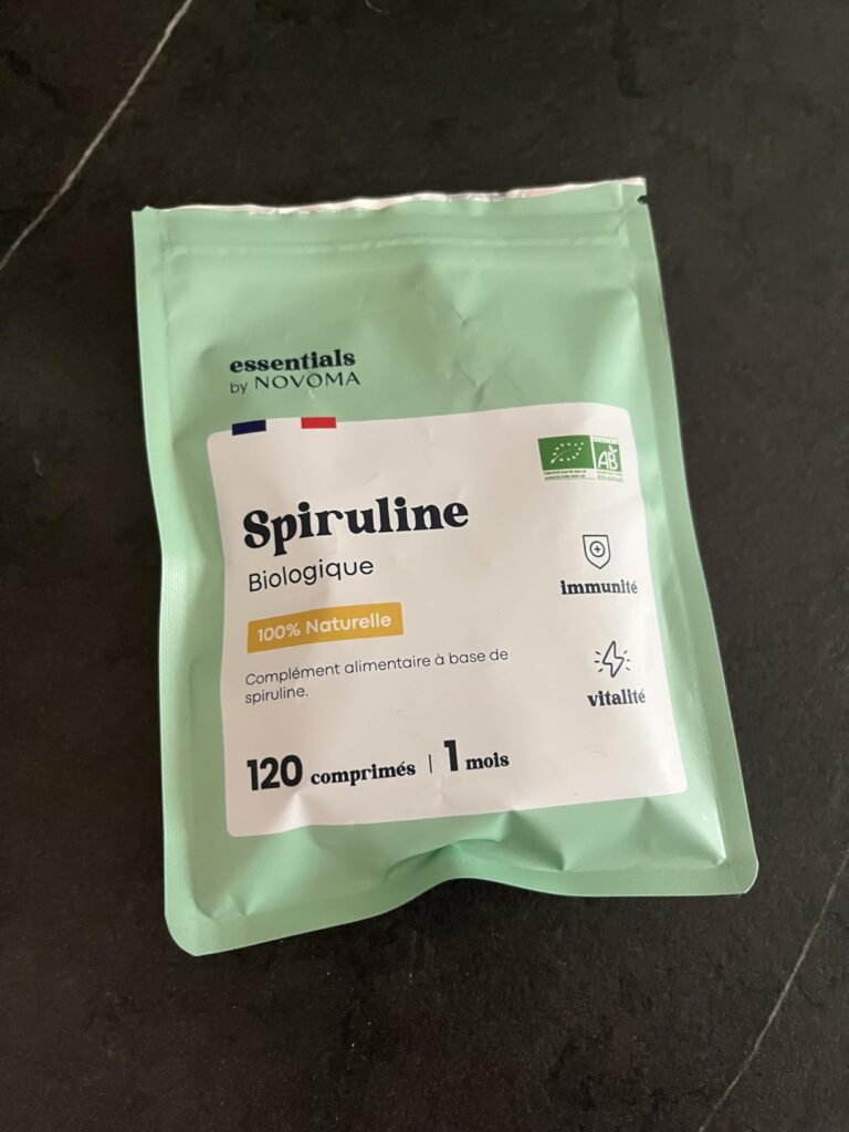 Sachet de spiruline de la marque Novoma, posé sur une table sombre.