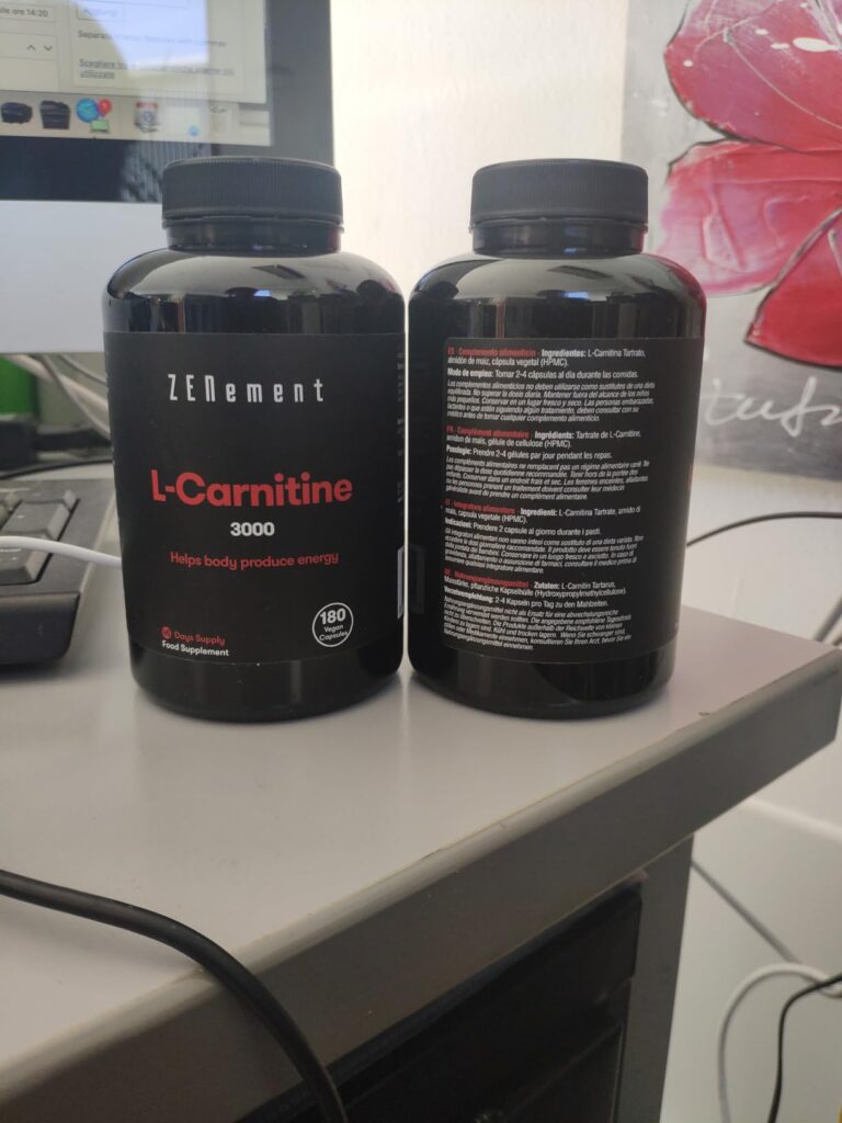 Deux flacons de L-Carnitine sur un bureau. L'un est visible de face, l'autre par l'arrière, montrant l'étiquette nutritionnel...