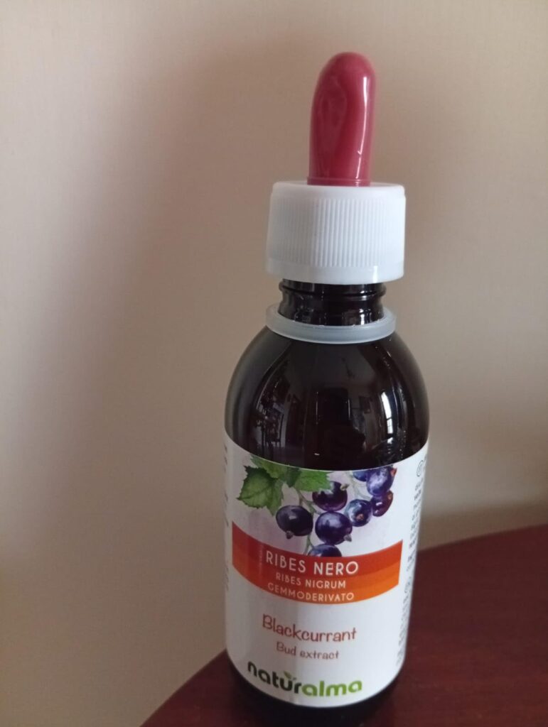 Bouteille d'extrait de bourgeons de cassis sur une table, fond neutre. Visuel très proche du visuel 0.
