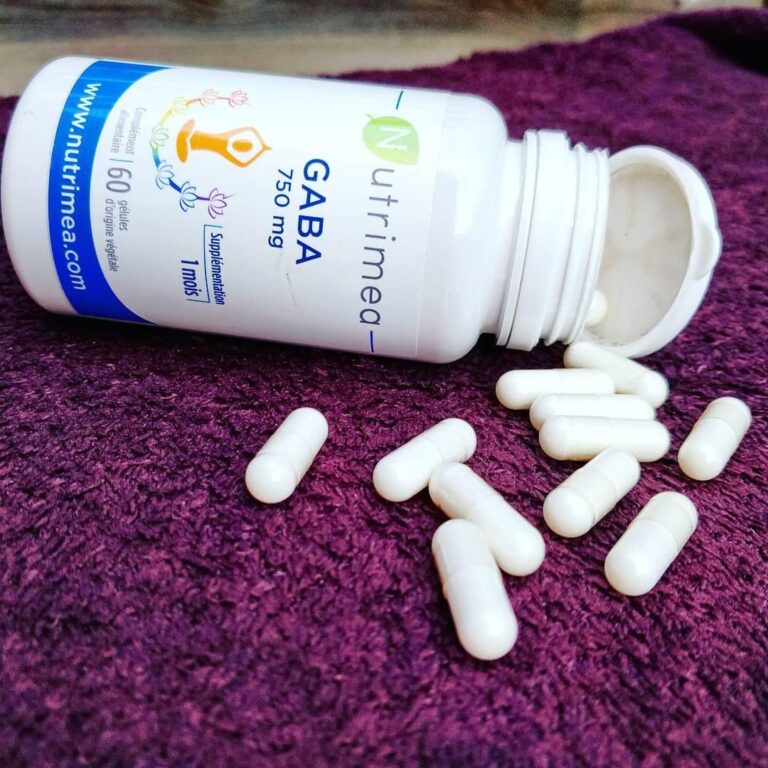Le flacon de GABA Nutriméa et des gélules blanches éparpillées sur une surface violette.