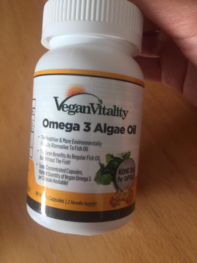 Flacon de compléments alimentaires Omega 3 Algae Oil Vegan Vitality tenu dans une main, vue légèrement différente du visuel 0...