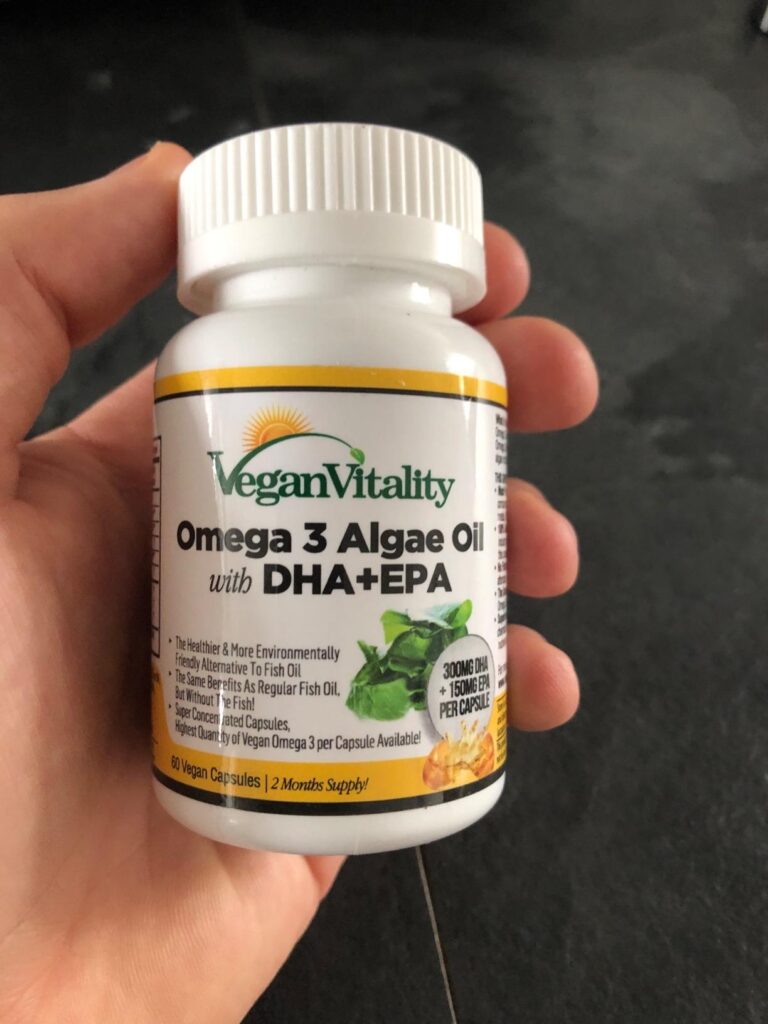 Flacon de compléments alimentaires Omega 3 Algae Oil Vegan Vitality tenu dans une main, avec la face avant visible.
