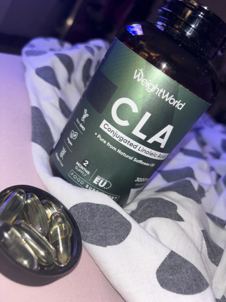Bouteille de compléments alimentaires CLA sur un tissu avec un petit récipient rempli de gélules.