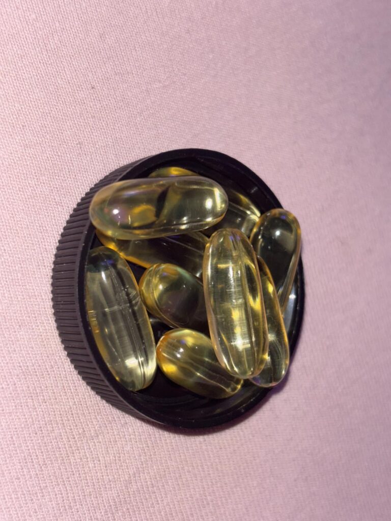 Gros plan sur plusieurs gélules de CLA dans un bouchon de bouteille.