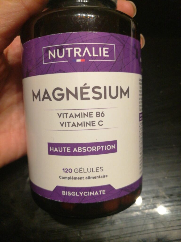 L'avant du flacon de magnésium, avec la marque et les arguments marketing, tenu à la main.