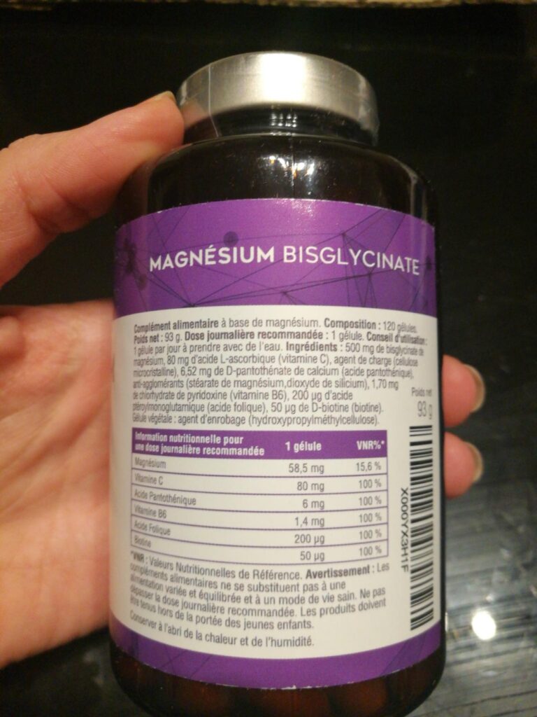L'arrière du flacon, axé sur la liste des ingrédients et la valeur nutritionnelle, tenu à la main.