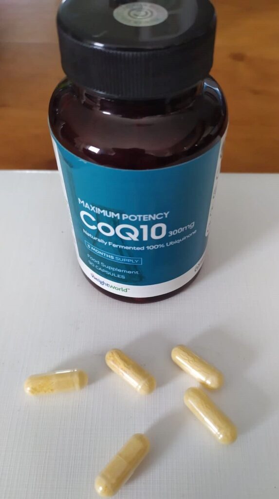 Flacon de compléments alimentaires avec plusieurs capsules à l'extérieur, posées sur une table.