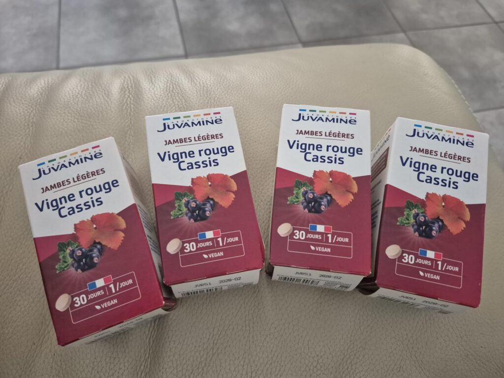 Quatre boîtes de compléments alimentaires JuvaSanté Jambes Légères Vigne Rouge Cassis posées sur un canapé.