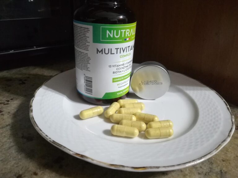 Bouteille de compléments alimentaires et gélules, posées sur une assiette dans une cuisine.
