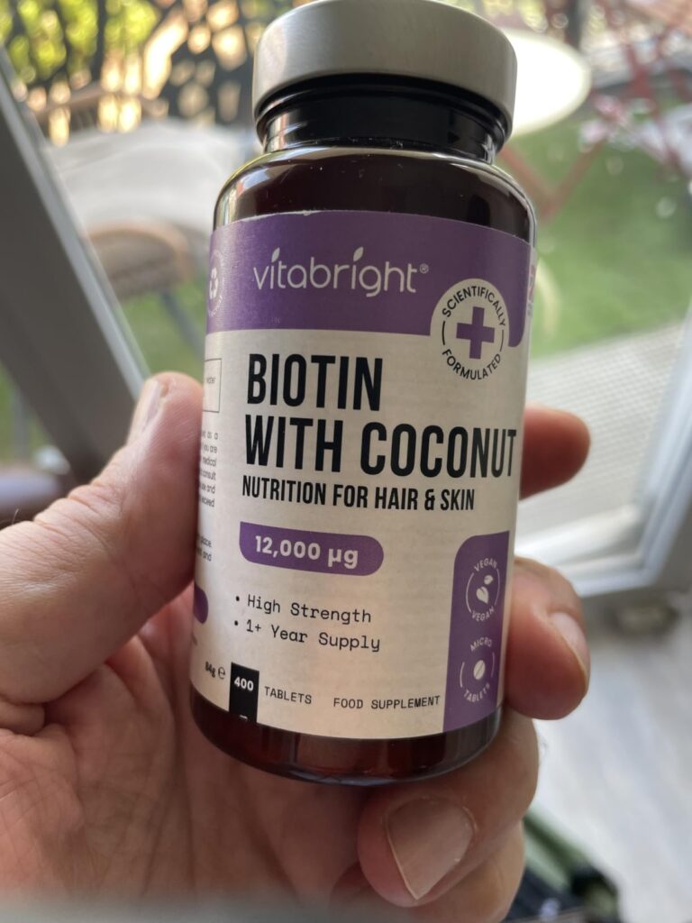 Flacon de biotine Vitabright en gros plan dans une main. L'étiquette est bien visible.