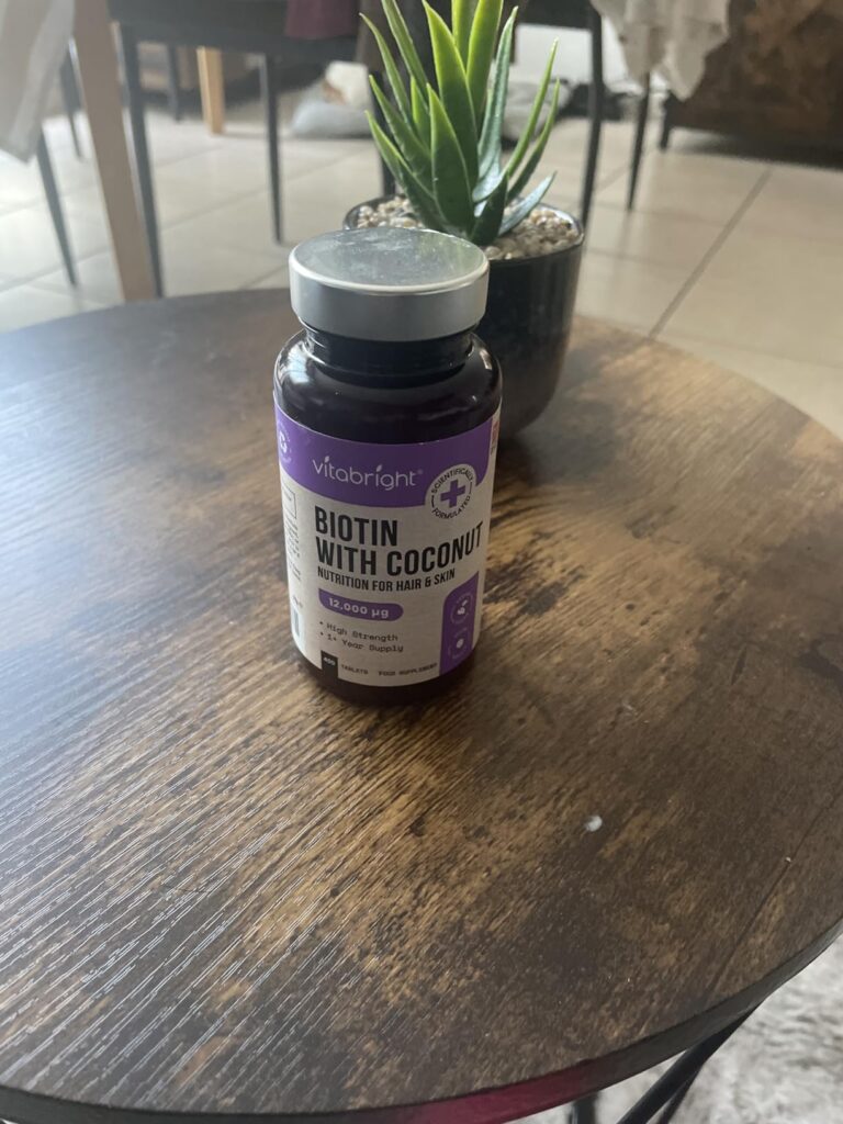 Flacon de biotine Vitabright posé sur une table basse en bois, à côté d'une plante. Même flacon que le visuel 0.
