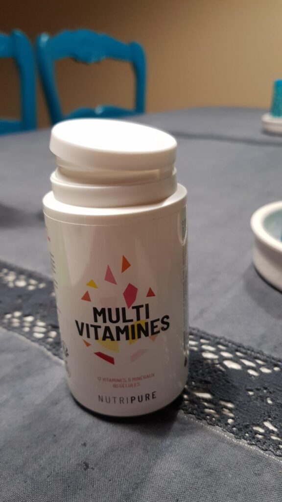 Bouteille de multivitamines sur une table avec une nappe, angle différent du visuel 0.