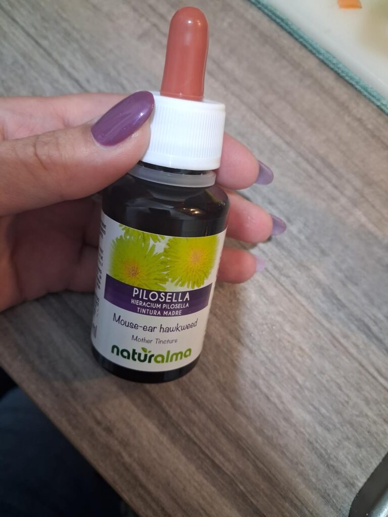 Une femme tient dans sa main le flacon de piloselle, le produit est mis en situation.