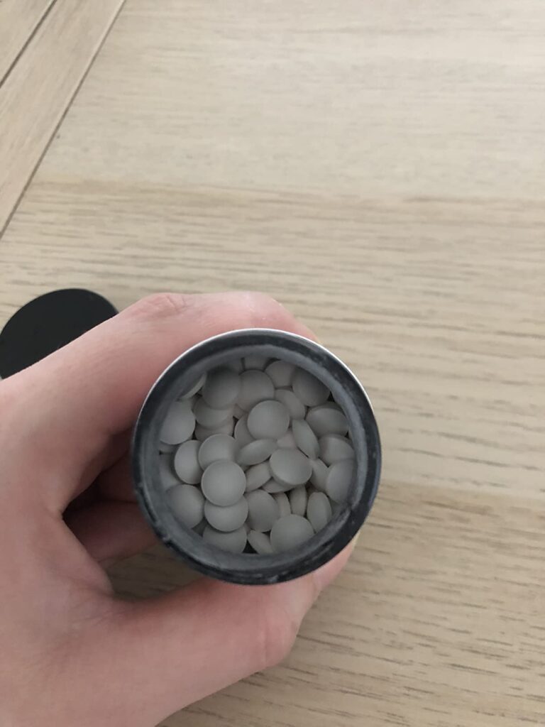 Gros plan sur le pilulier ouvert avec les cachets blancs ronds.