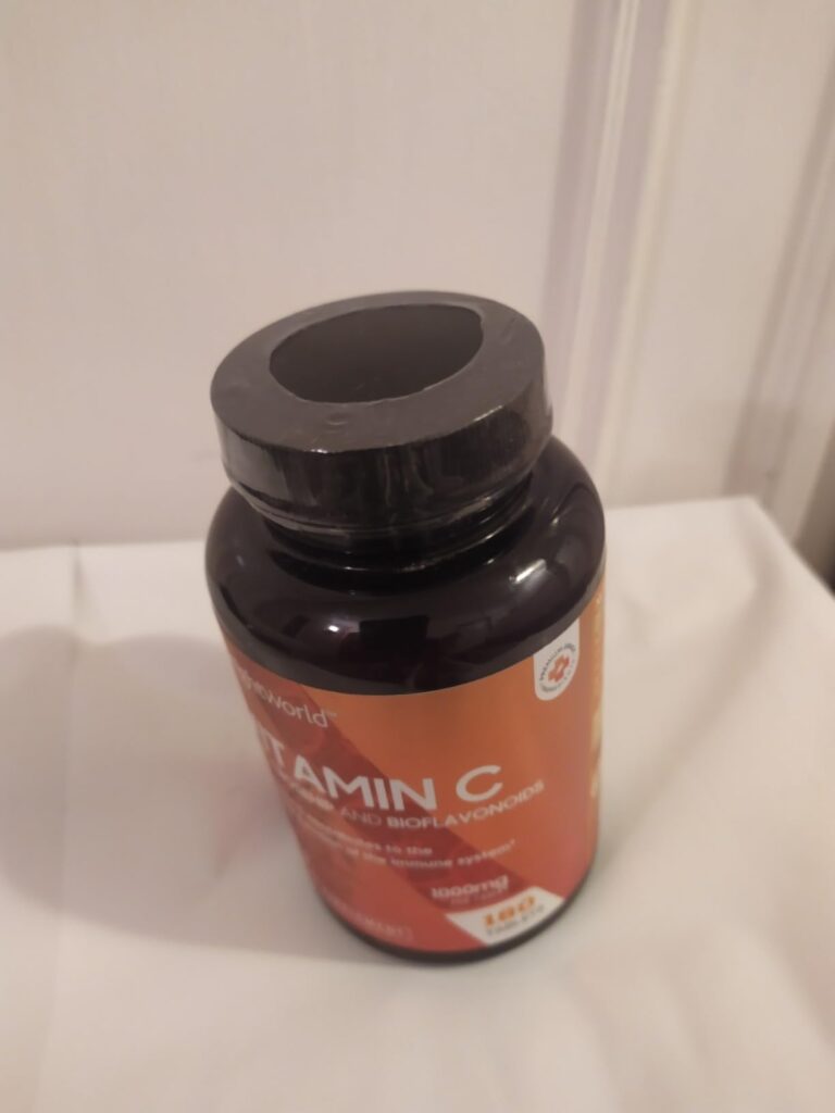 Le flacon fermé de vitamine C est posé sur une surface blanche.