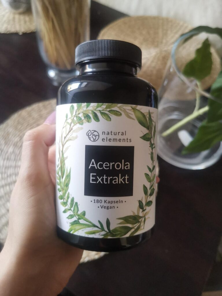 Une main tient la bouteille de gélules d'acérola, montrant l'étiquette avec plus de détails.