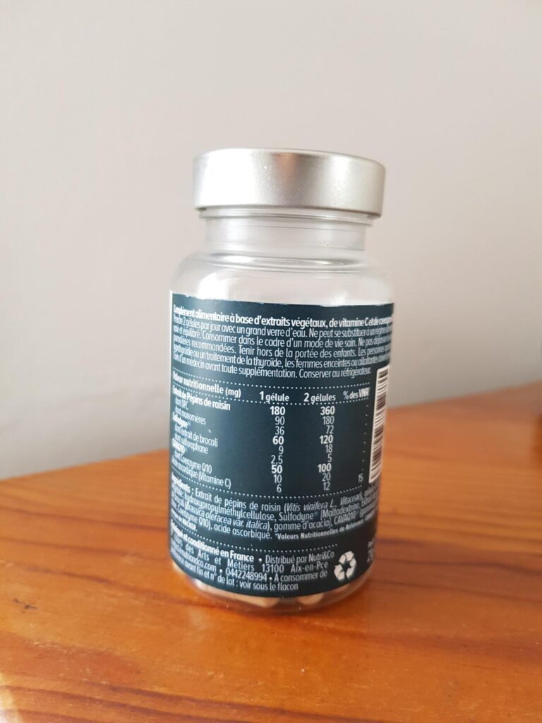 Flacon de Nutri & Co L'Antioxydant sur une table en bois, avec l'étiquette arrière visible, présentant la composition et le m...