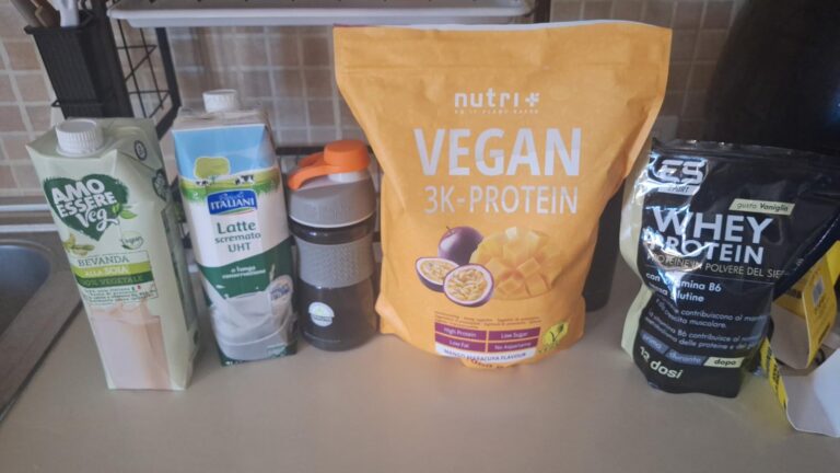 L'image montre un sachet de protéine Vegan, un sachet de protéine Whey, et deux bouteilles de lait à côté d'un shaker. Le tou...