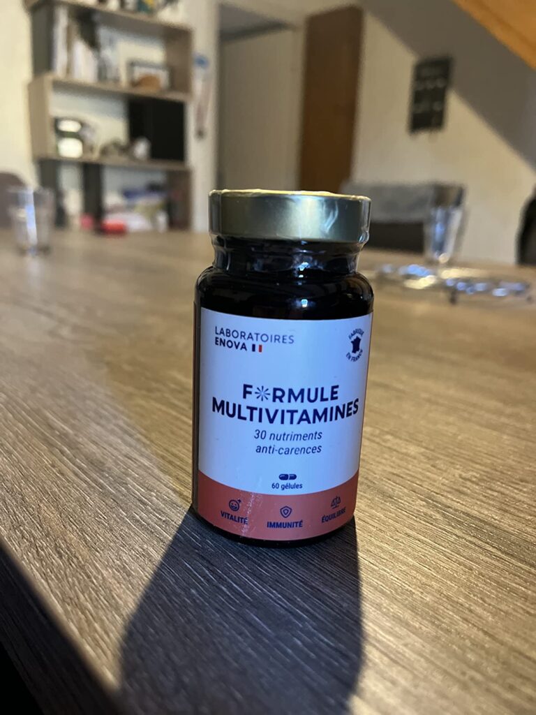 Le flacon de multivitamines posé sur une table en bois, dans un intérieur.