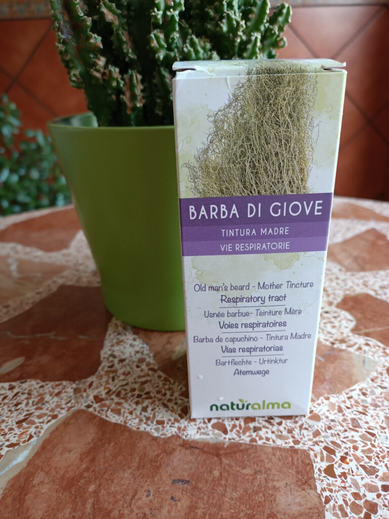 Boîte du produit, vue de face, posée sur une table avec une plante en arrière-plan.