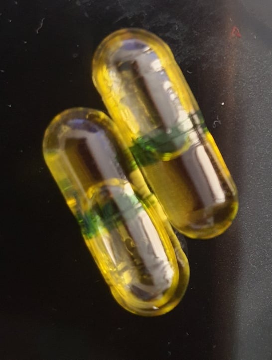 Deux gélules d'huile de bourrache et onagre, en gros plan, montrant la capsule transparente remplie d'huile.