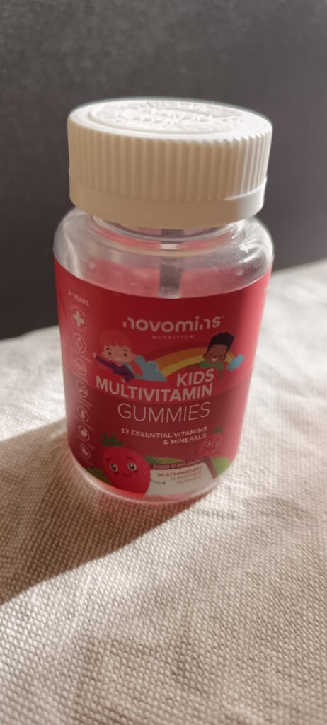 Bouteille de multivitamines pour enfants, vue de face, sur fond clair. Le flacon est fermé par un bouchon blanc.