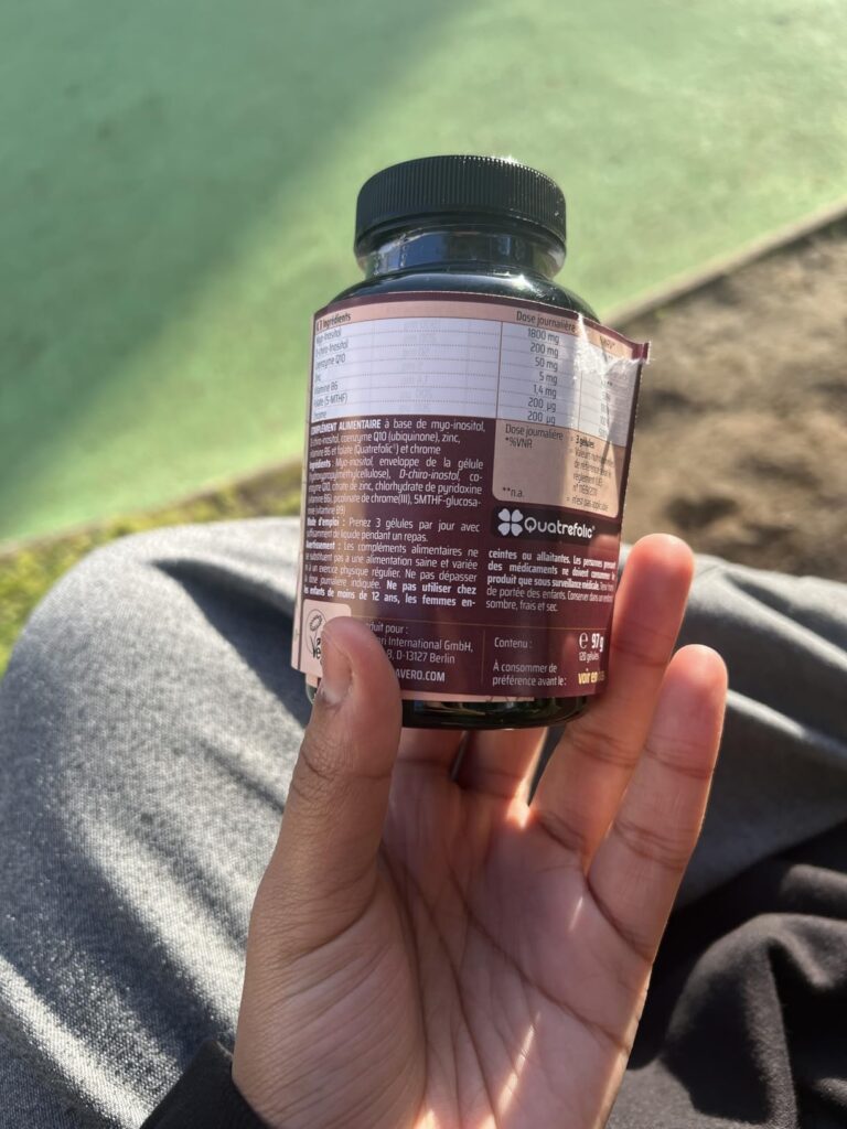 Vue arrière du flacon montrant les étiquettes nutritionnelles, tenu à la main.