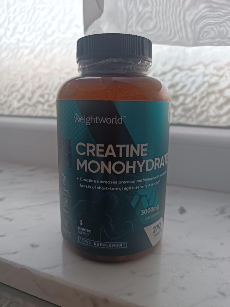 Bouteille de créatine monohydrate posée sur un rebord de fenêtre, prise de face.